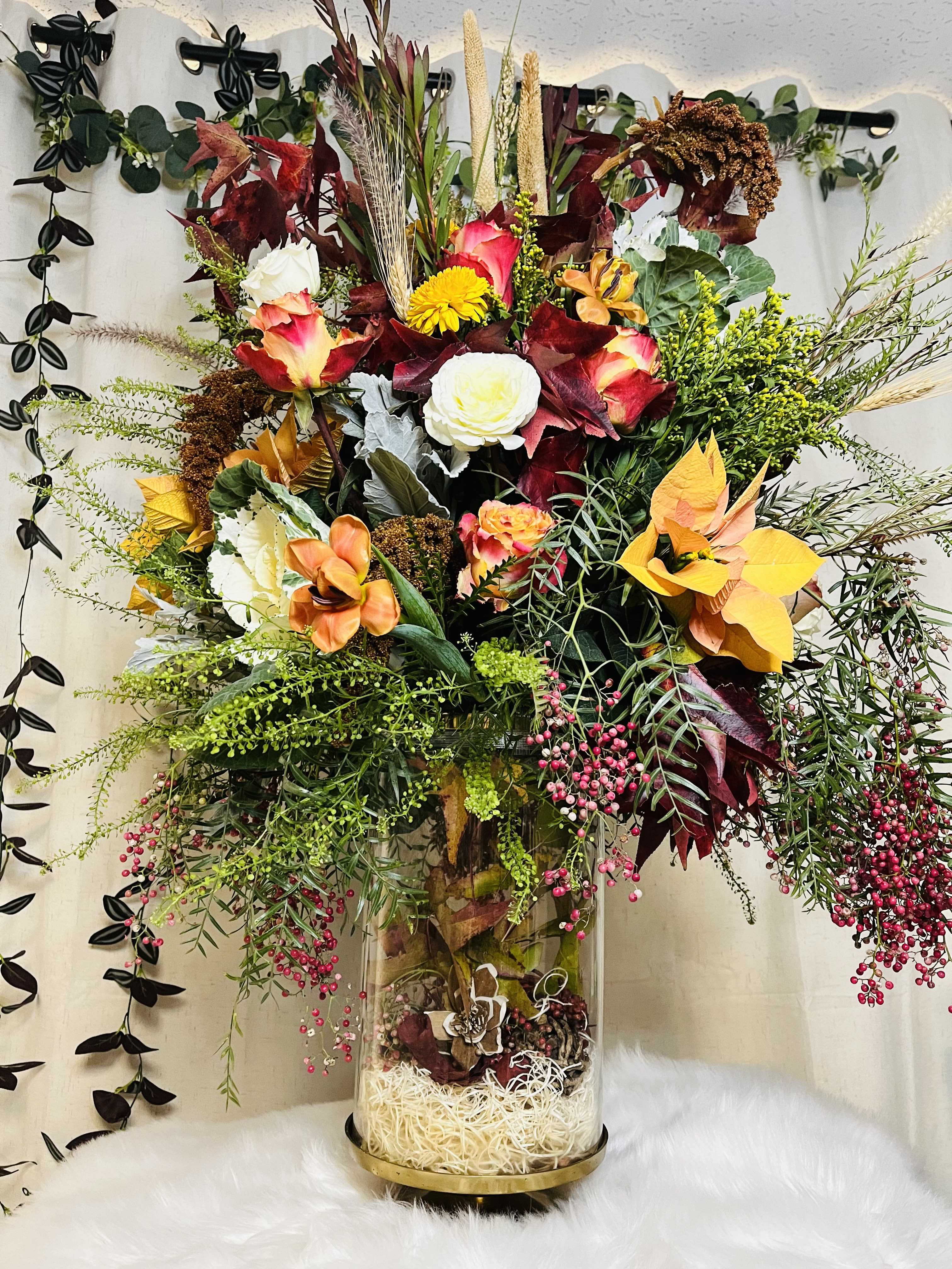 Tall mixed floral arrangement in a clear glass vase with autumn colors