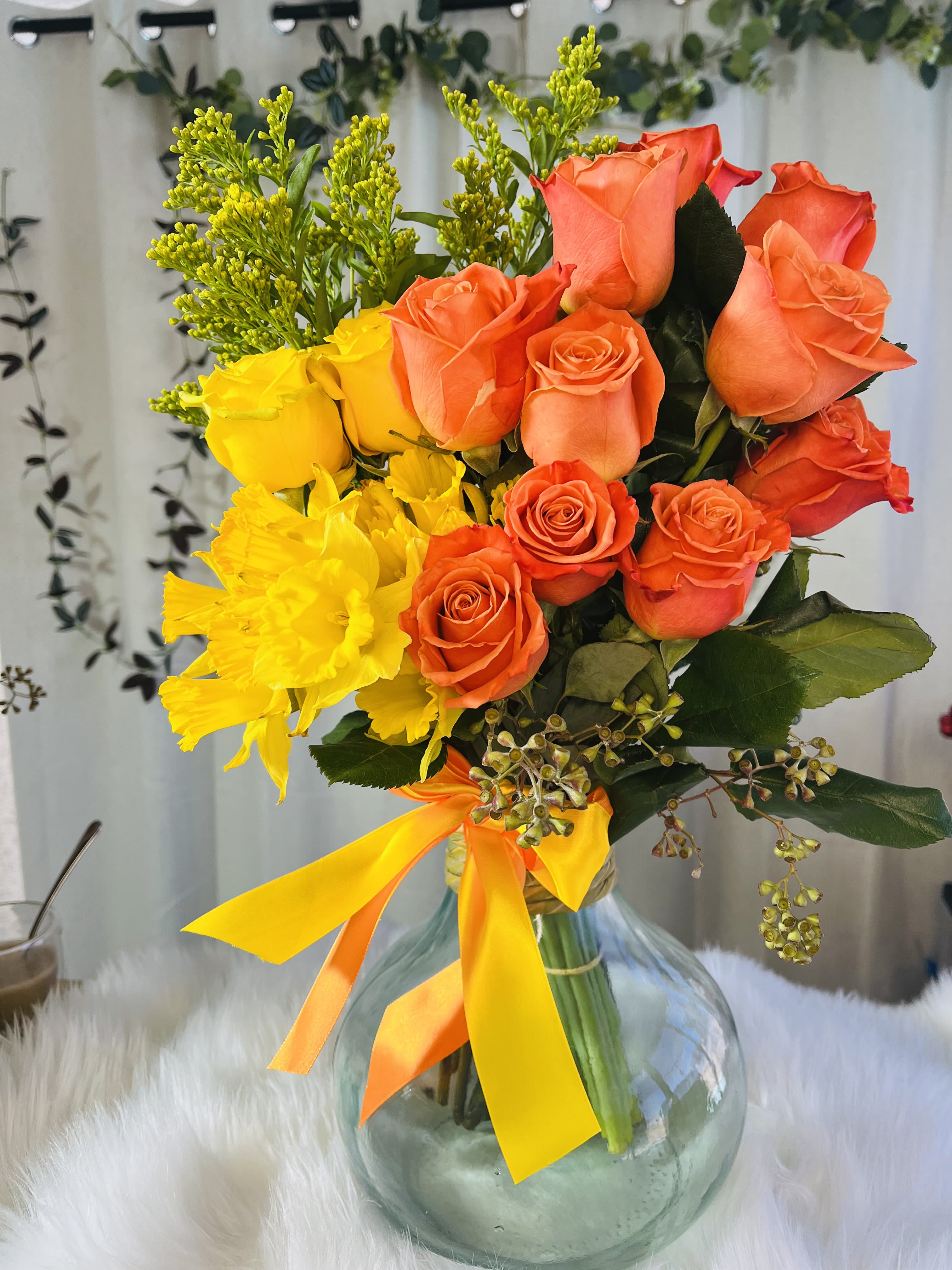 Bouquet of orange and yellow roses in a glass vase with ribbon