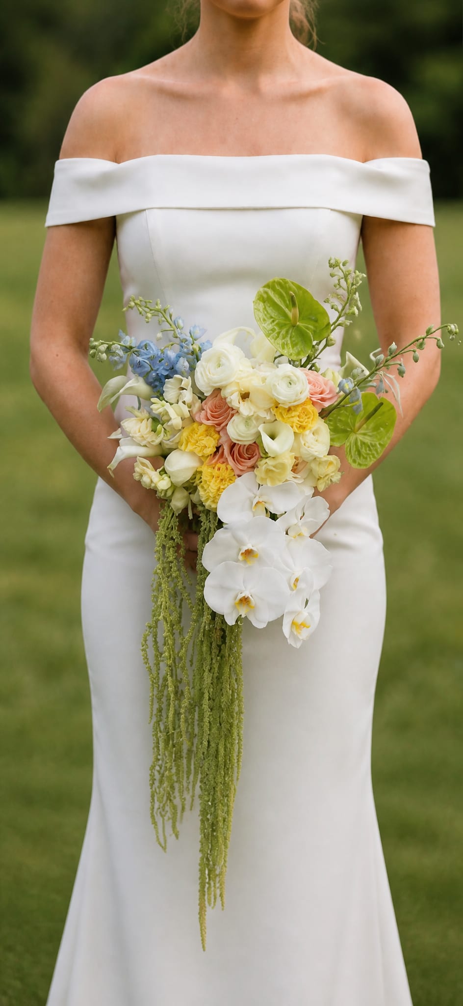 Bride holding a cascading bouquet of white, peach, yellow, and blue flowers