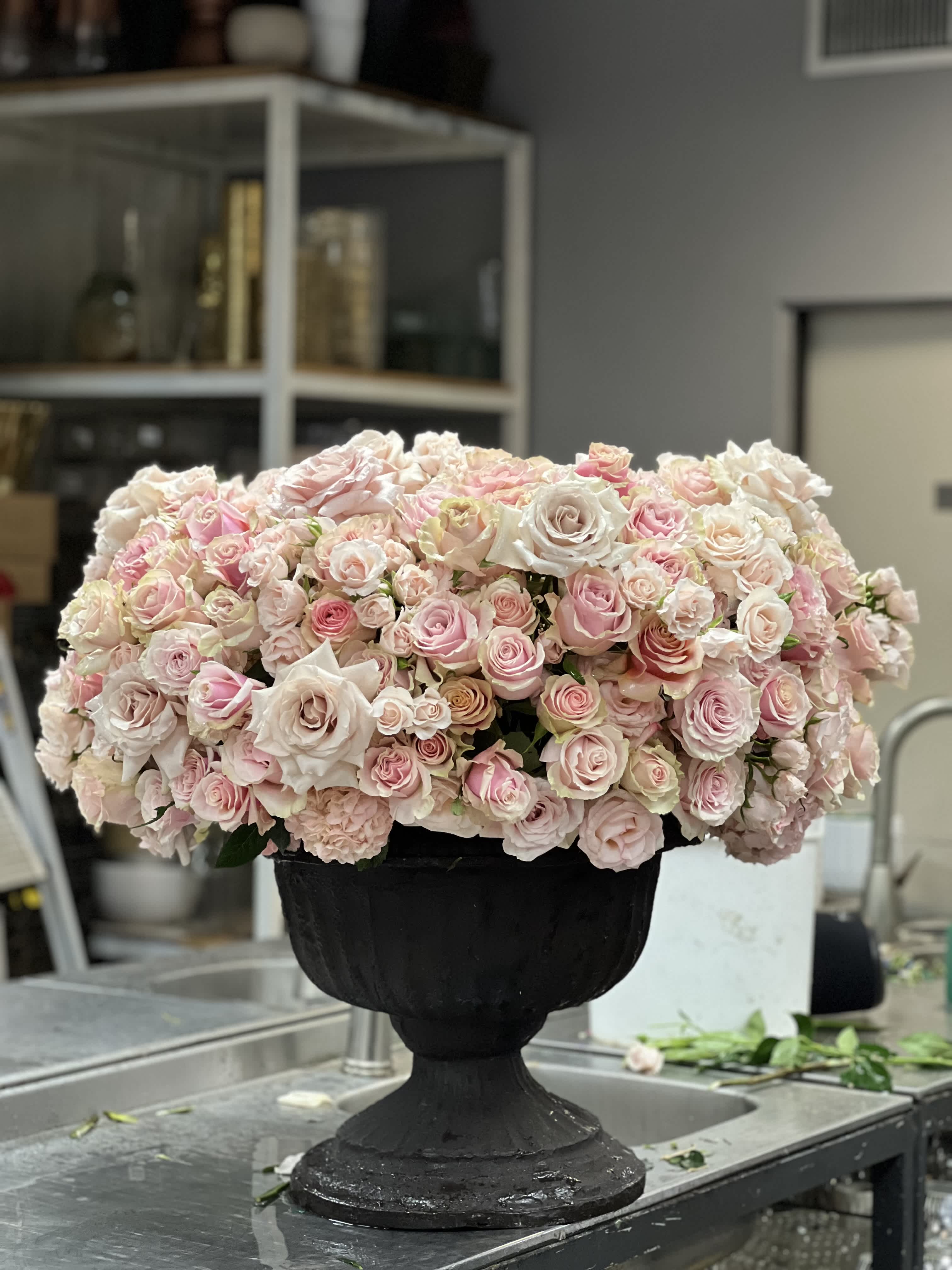 Large arrangement of pale pink and white roses in a black urn vase