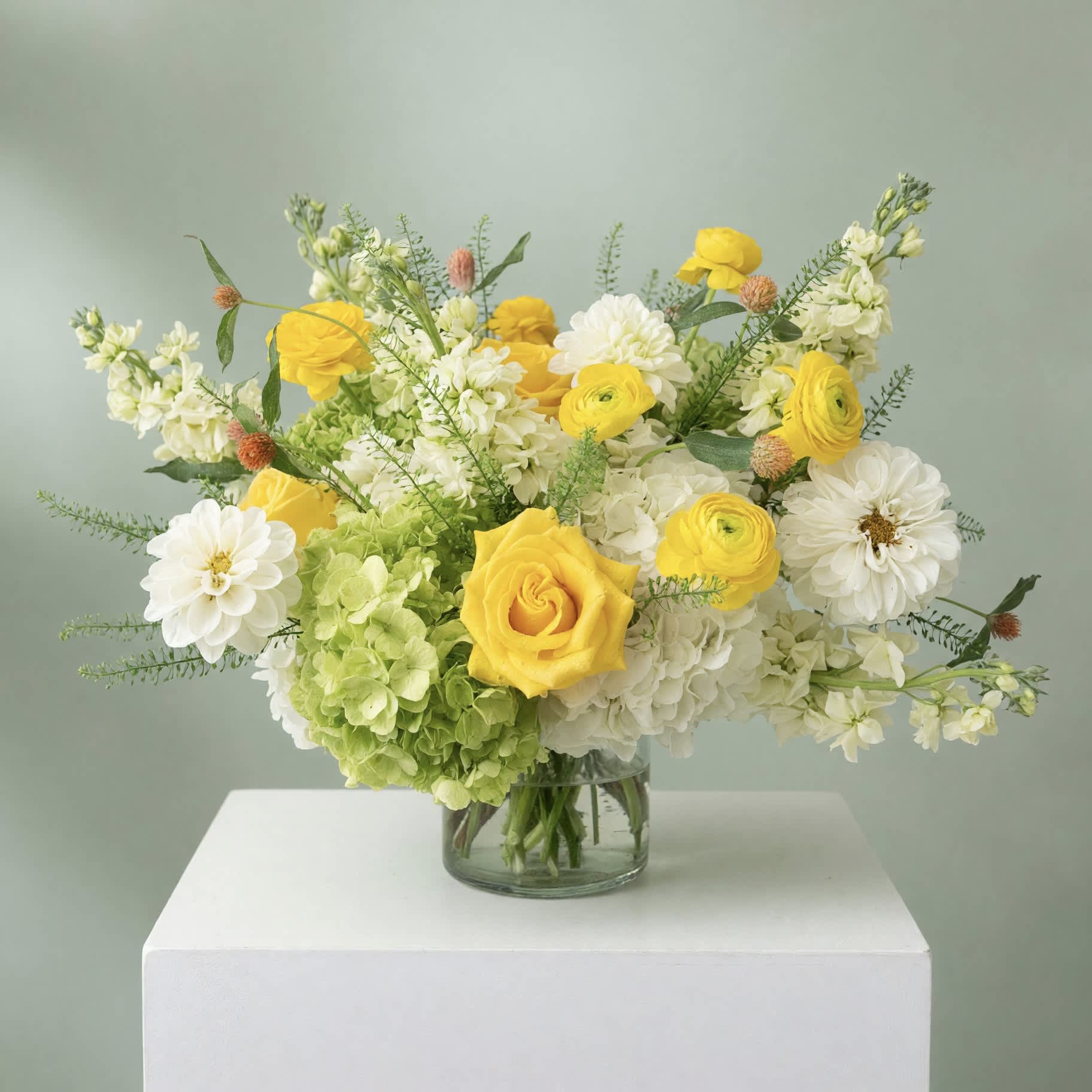 Yellow and white flowers arranged in a clear glass vase