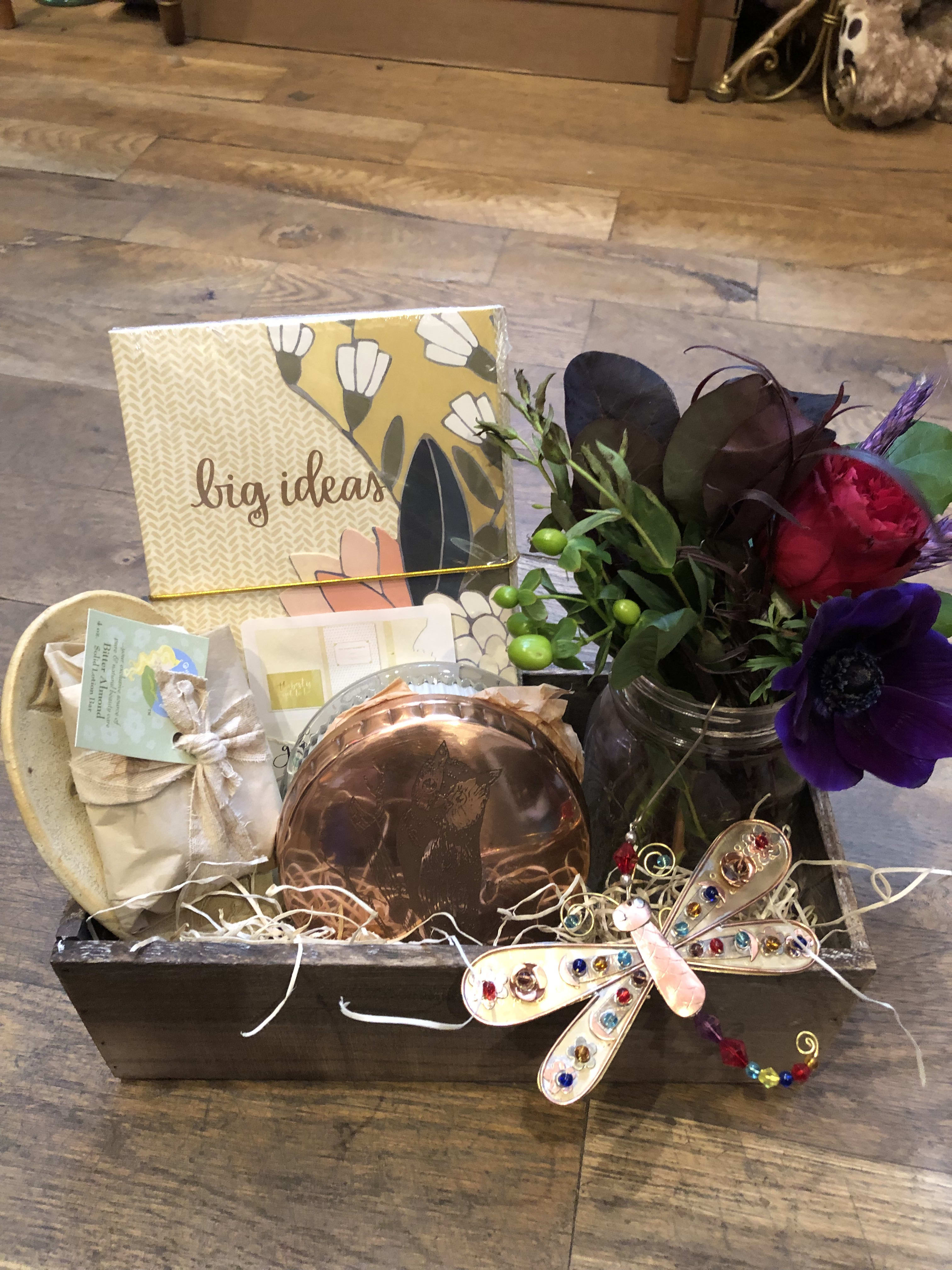 Gift basket with a small flower arrangement, candle, and stationery items