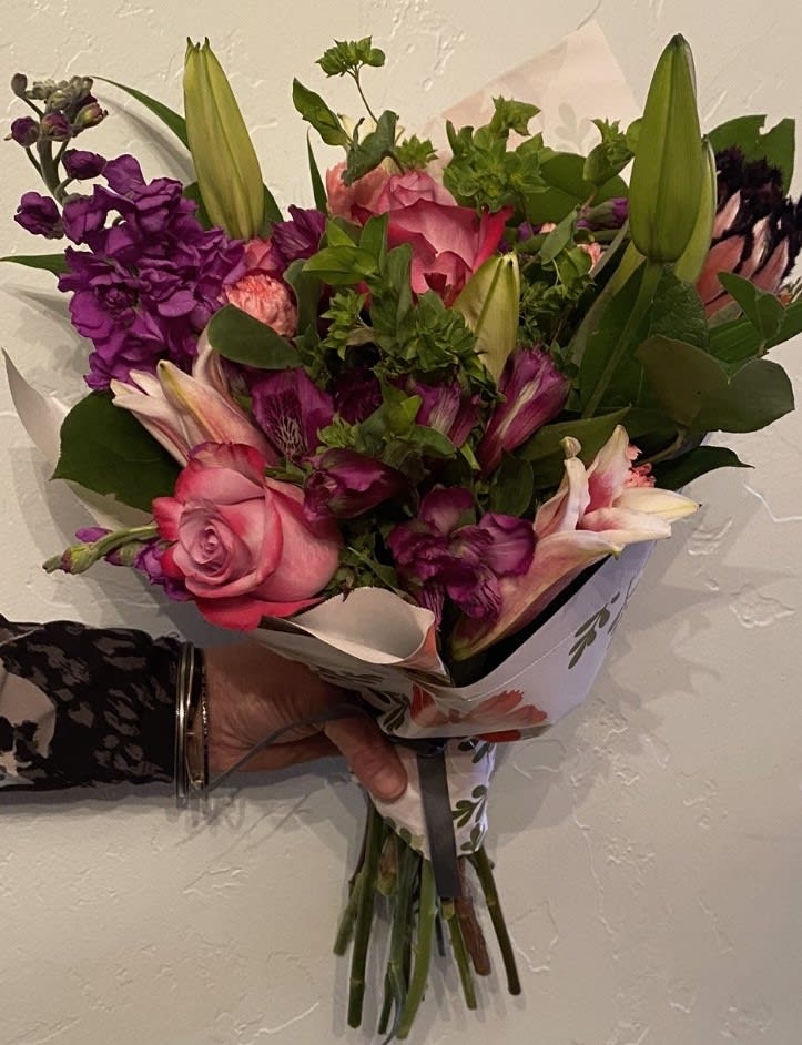 Handheld bouquet of pink and purple flowers with lilies and roses