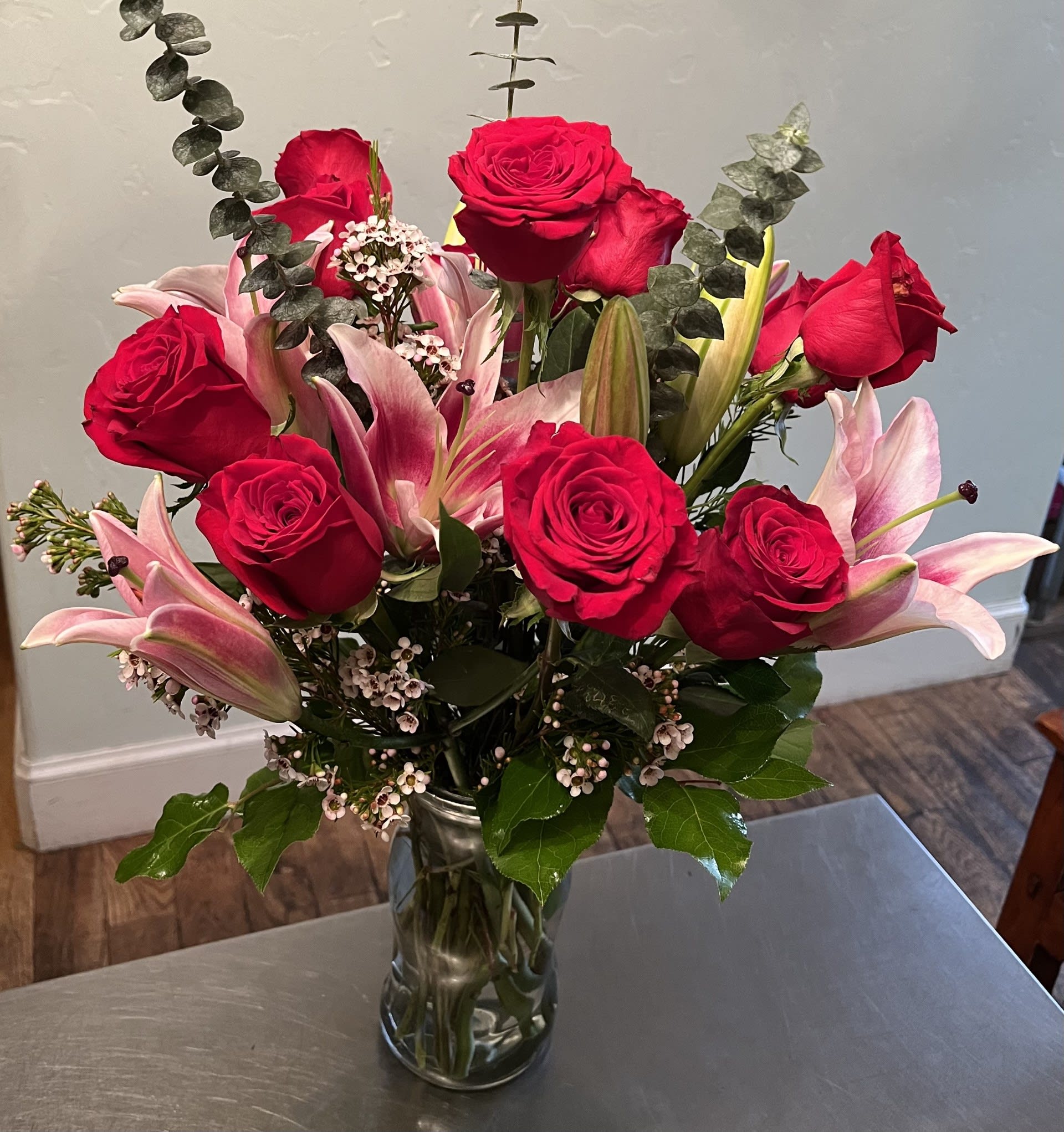 Red roses and pink lilies arranged in a clear glass vase.
