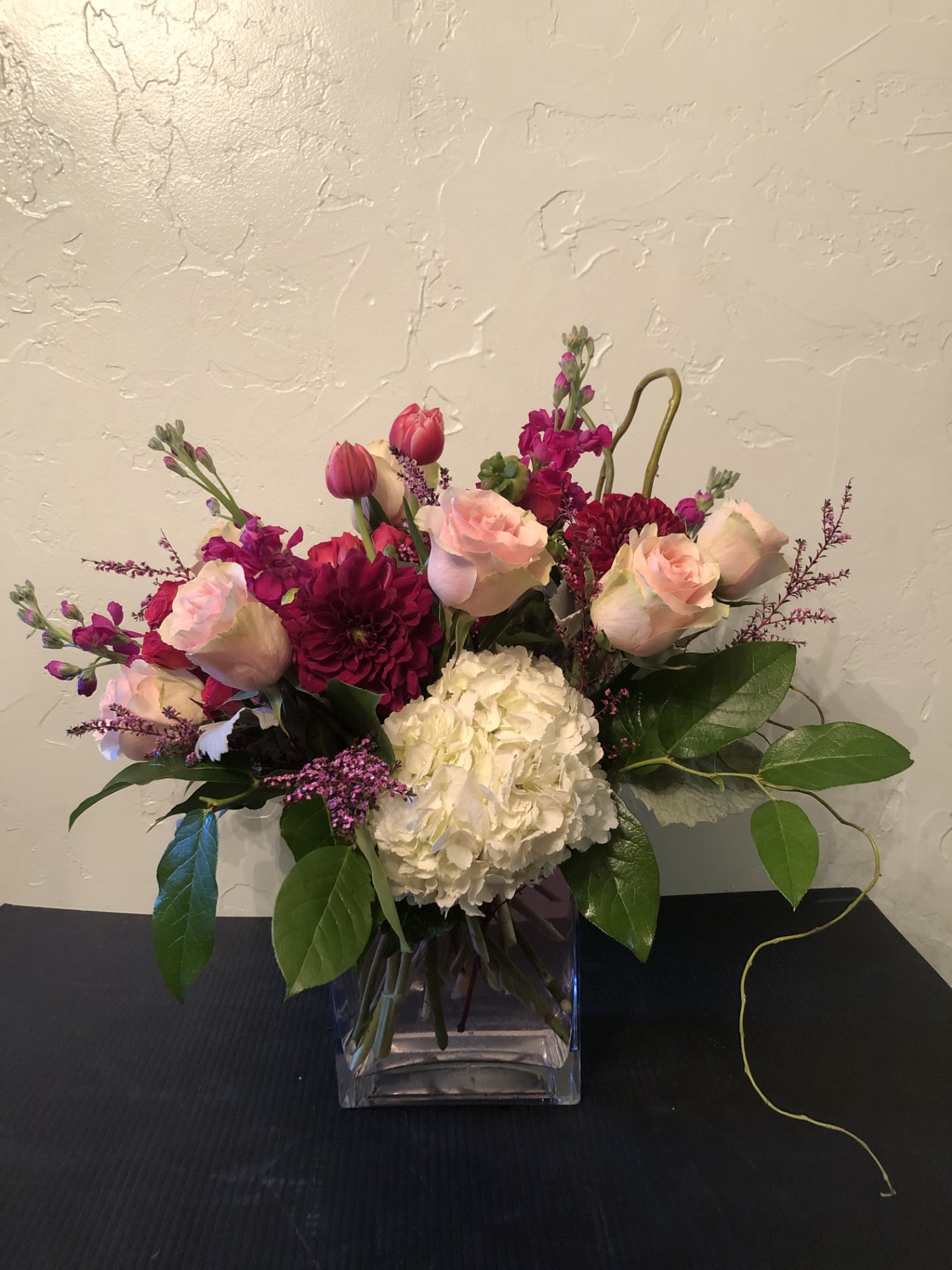 Pink roses and magenta blooms in a clear glass vase