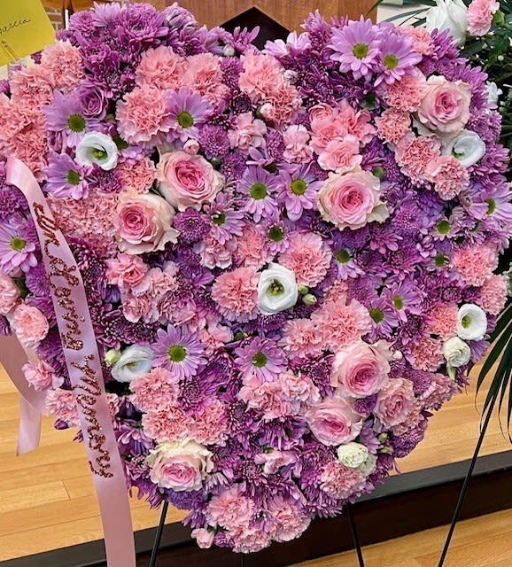 Heart-shaped bouquet of pink and purple flowers with a ribbon
