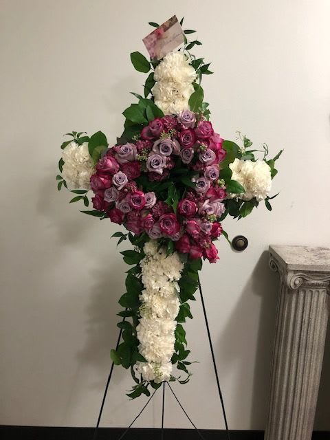 Standing floral cross with pink roses and white flowers on an easel