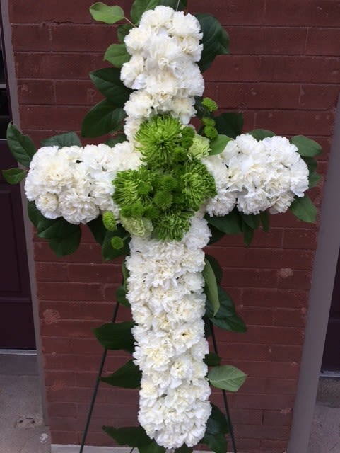 White and green floral cross arrangement on a stand