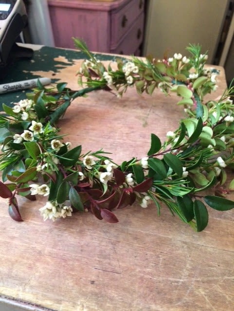 Floral crown with small white blossoms and mixed greenery on a table