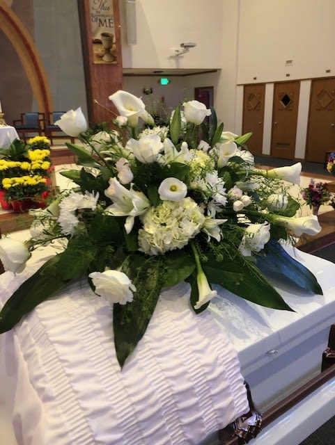 White funeral casket spray with calla lilies and roses