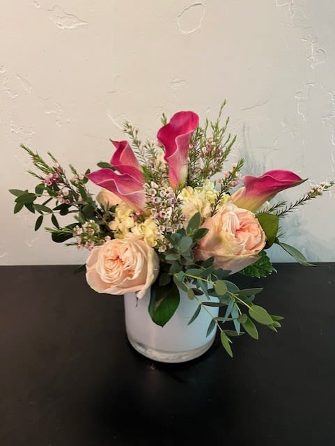 Pink calla lilies and blush roses in a white vase