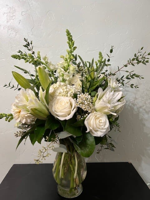 White roses and lilies arranged in a clear glass vase