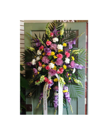 Tall standing spray of mixed pink, purple, white, and yellow flowers