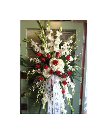 Tall standing floral spray with white flowers and red roses on a ribboned easel
