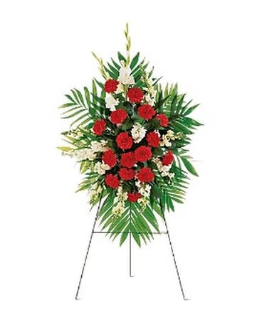 Standing floral spray with red carnations and white flowers on an easel
