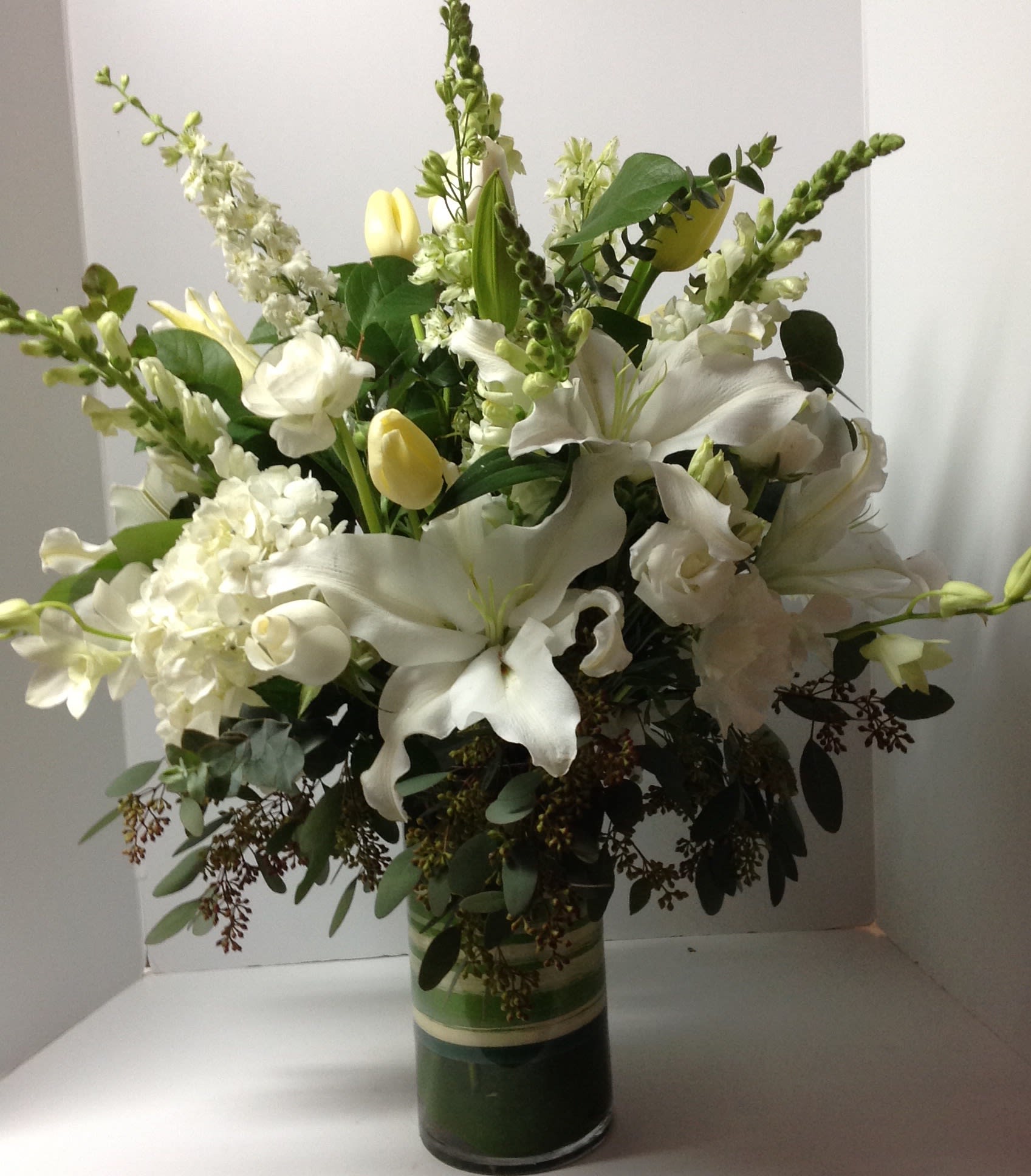 White lilies and tulips arranged in a glass vase