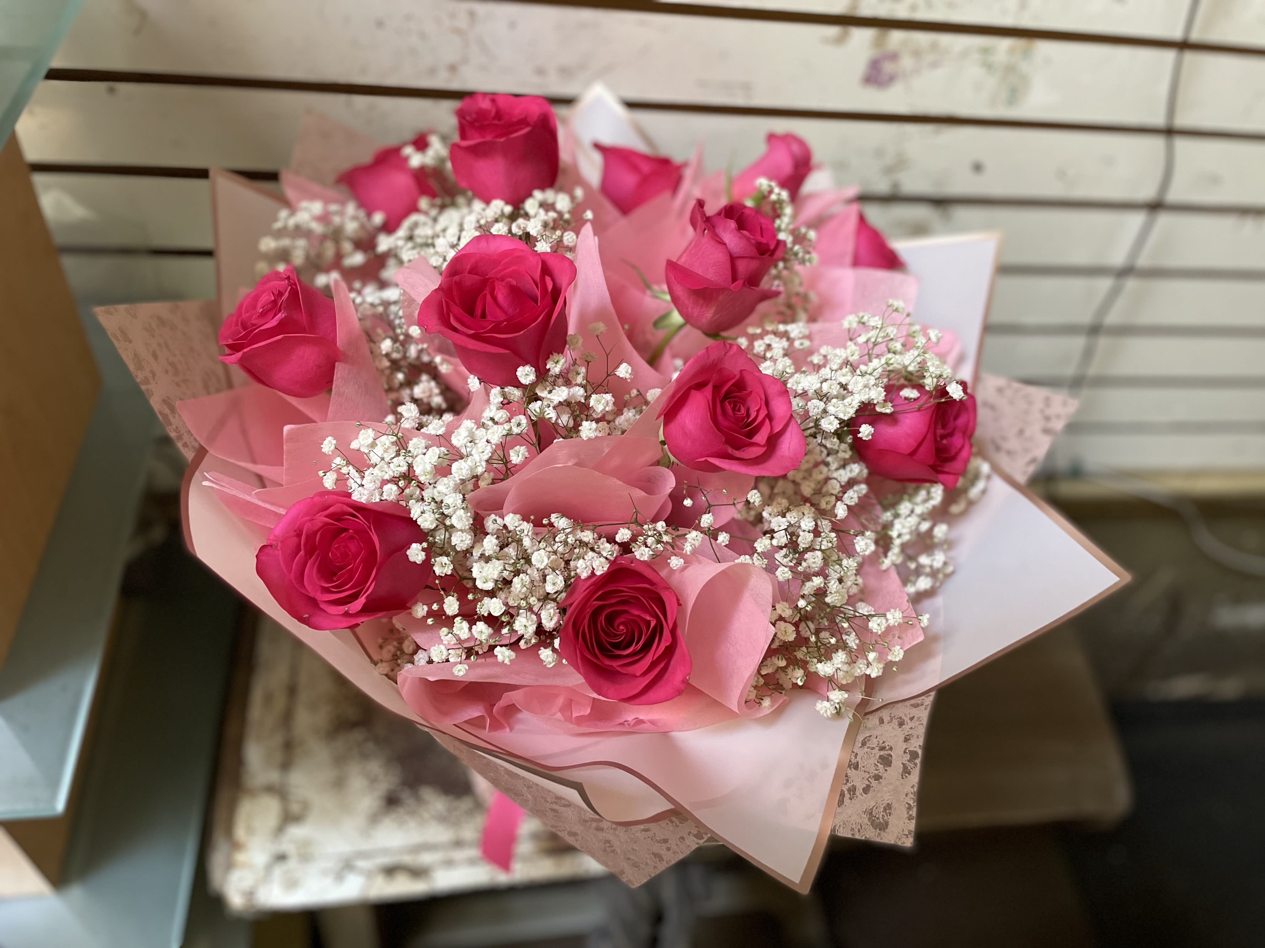 Bouquet of hot pink roses with white baby's breath in pink wrapping