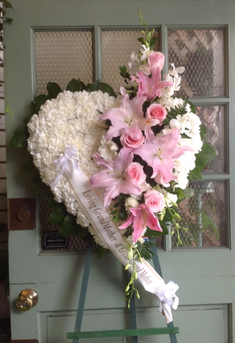 Heart-shaped funeral wreath with pink lilies, roses, and white flowers