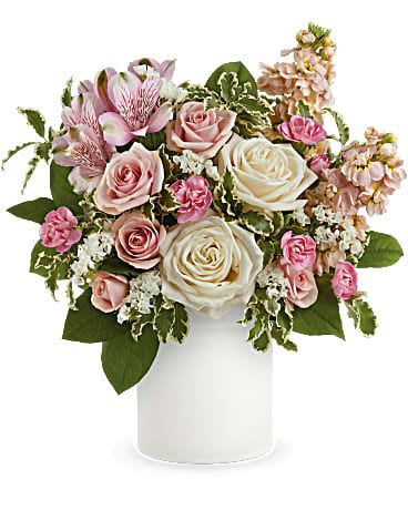 Pink and white roses, carnations, and alstroemeria arranged in a white cylinder vase