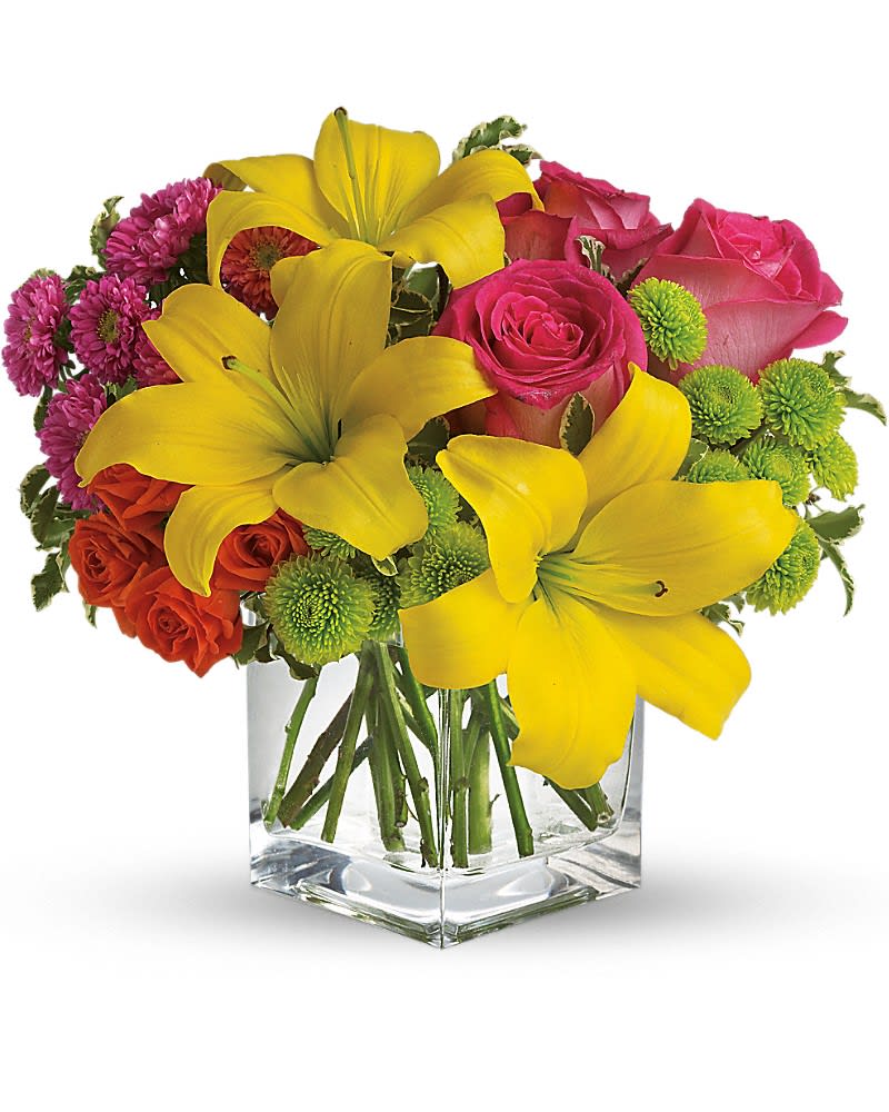 Bouquet of yellow lilies, pink roses, and purple flowers in a glass vase