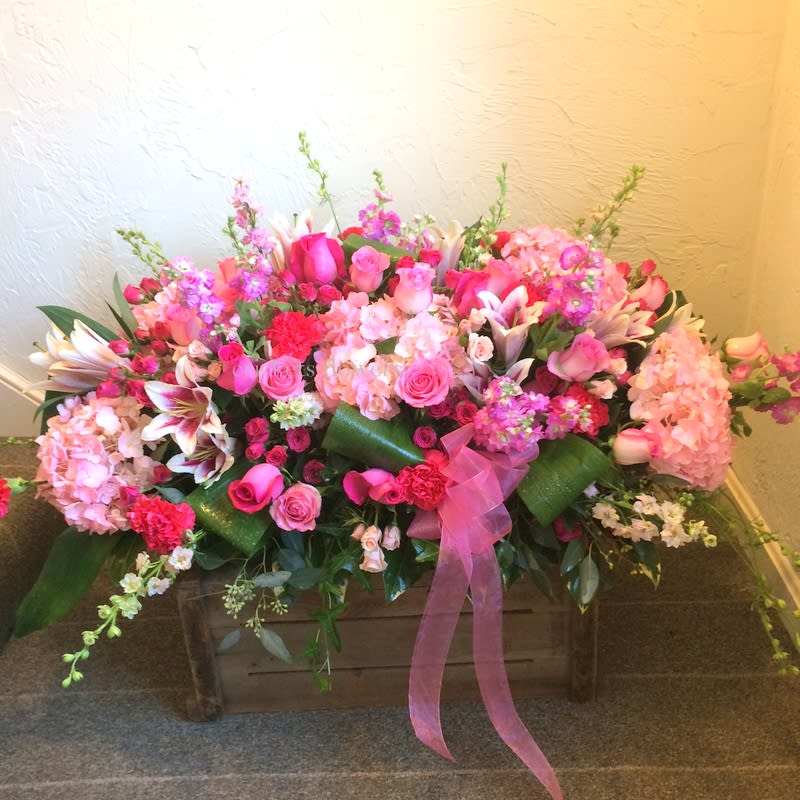 Large pink floral arrangement in a wooden box with a ribbon