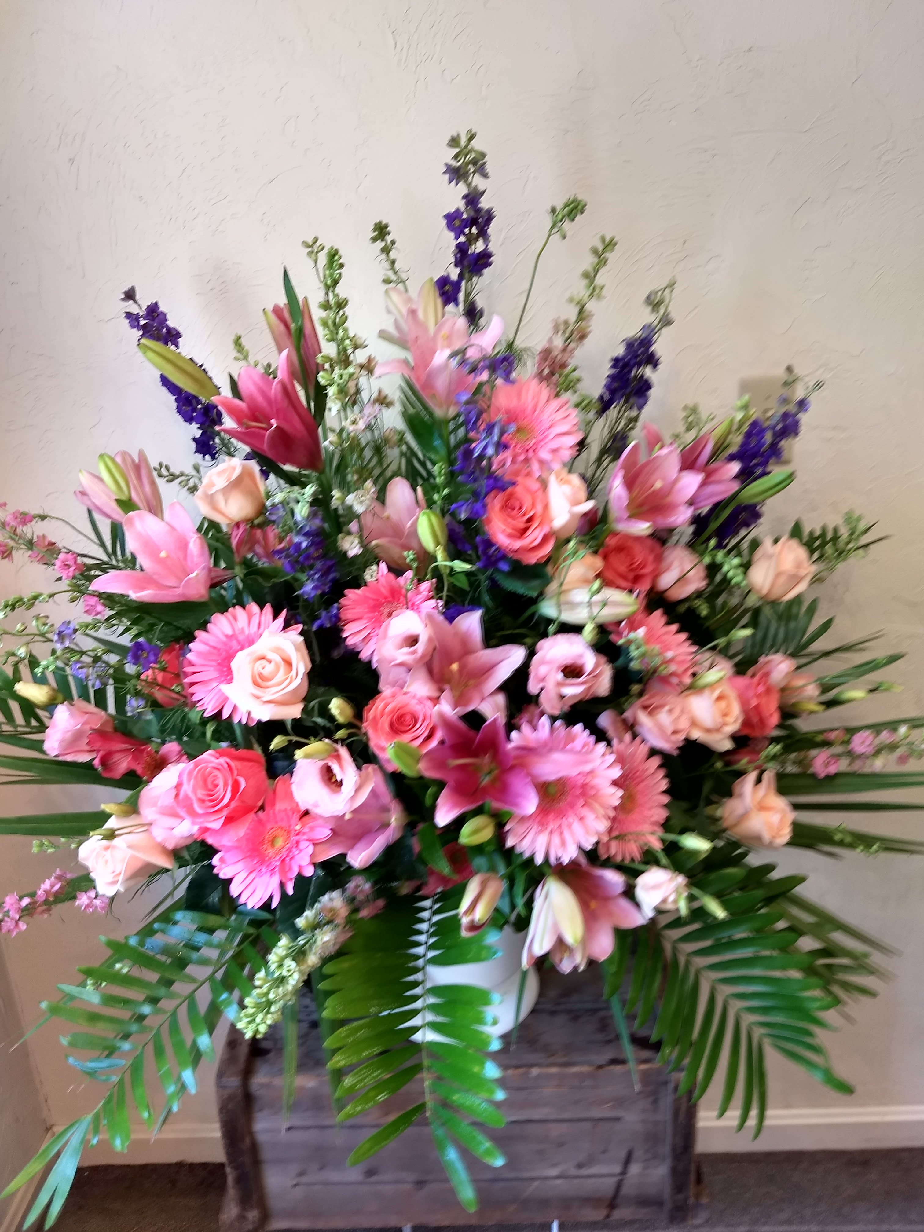  Loving Grace by Cricket's Flowers #cT2201A - Loving Grace Sympathy Basket A warm and peaceful expression of love and respect, this beautifully composed sympathy basket features a soft bounty of pastel blooms. Delicately arranged with peach and light pink roses, lavender and purple larkspur, pink Asiatic lilies, alstroemeria, gerberas, and lisianthus, it’s a graceful tribute suitable for the service or the home — offering comfort when it’s needed most.  Bouquet is approximately 32"H x 36"W.  **** Please note: 48 hour notice MAYBE REQUIRED We custom-design this arrangement using best-of-day seasonal flowers. This image is a general representation of its size and style and may not feature the exact flowers shown. Due to disruptions in the global supply chain and staff shortages, we may have to make last minute substitutions to your selected design. If we need to make significant changes we will call you first to get your approval*** Thank you for understanding.