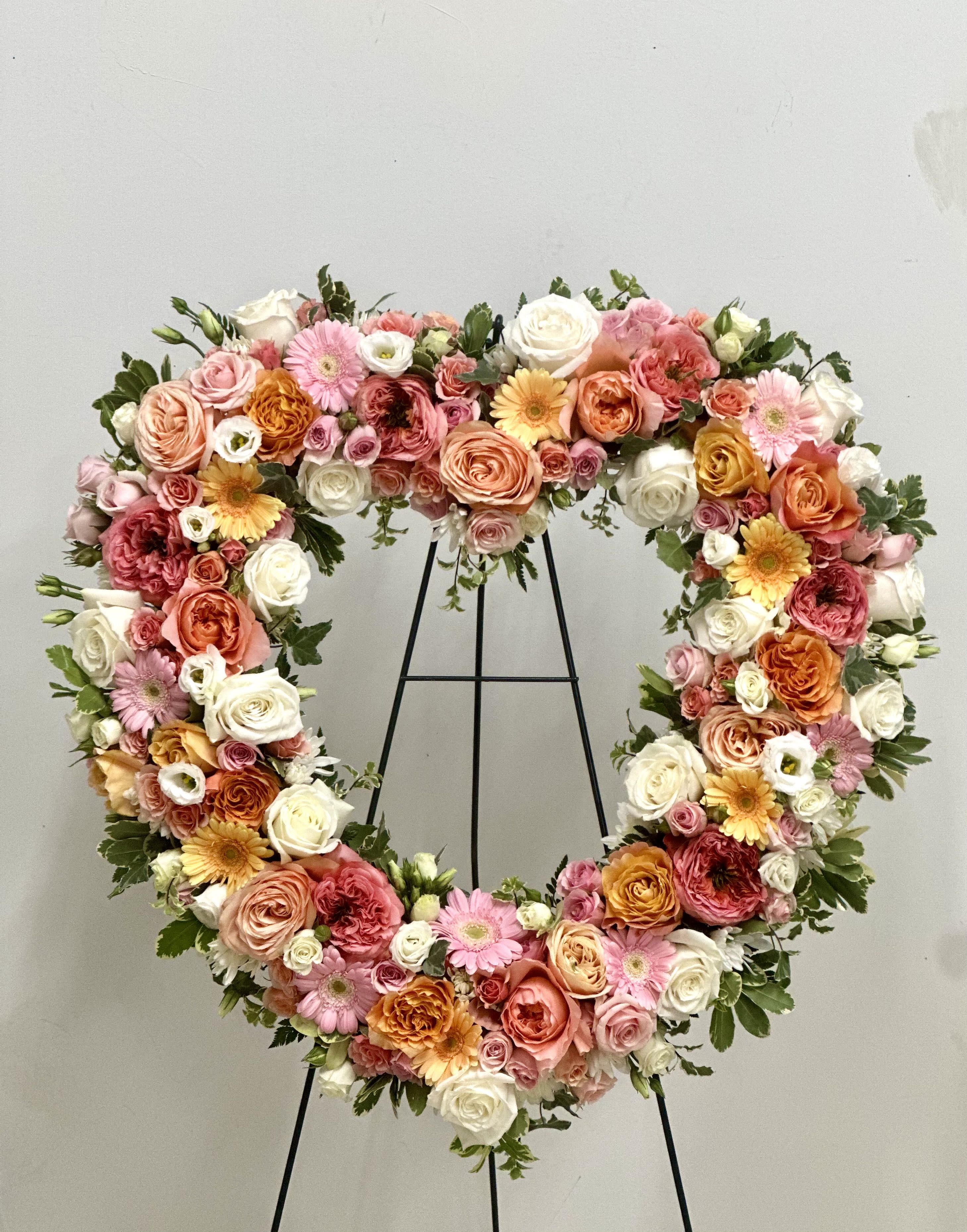 Heart-shaped floral wreath with pink, peach, white, and yellow blooms