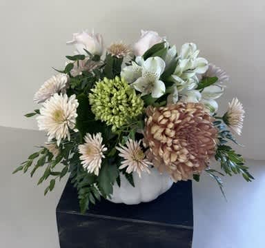 White and pale pink flowers arranged in a white pumpkin-shaped container
