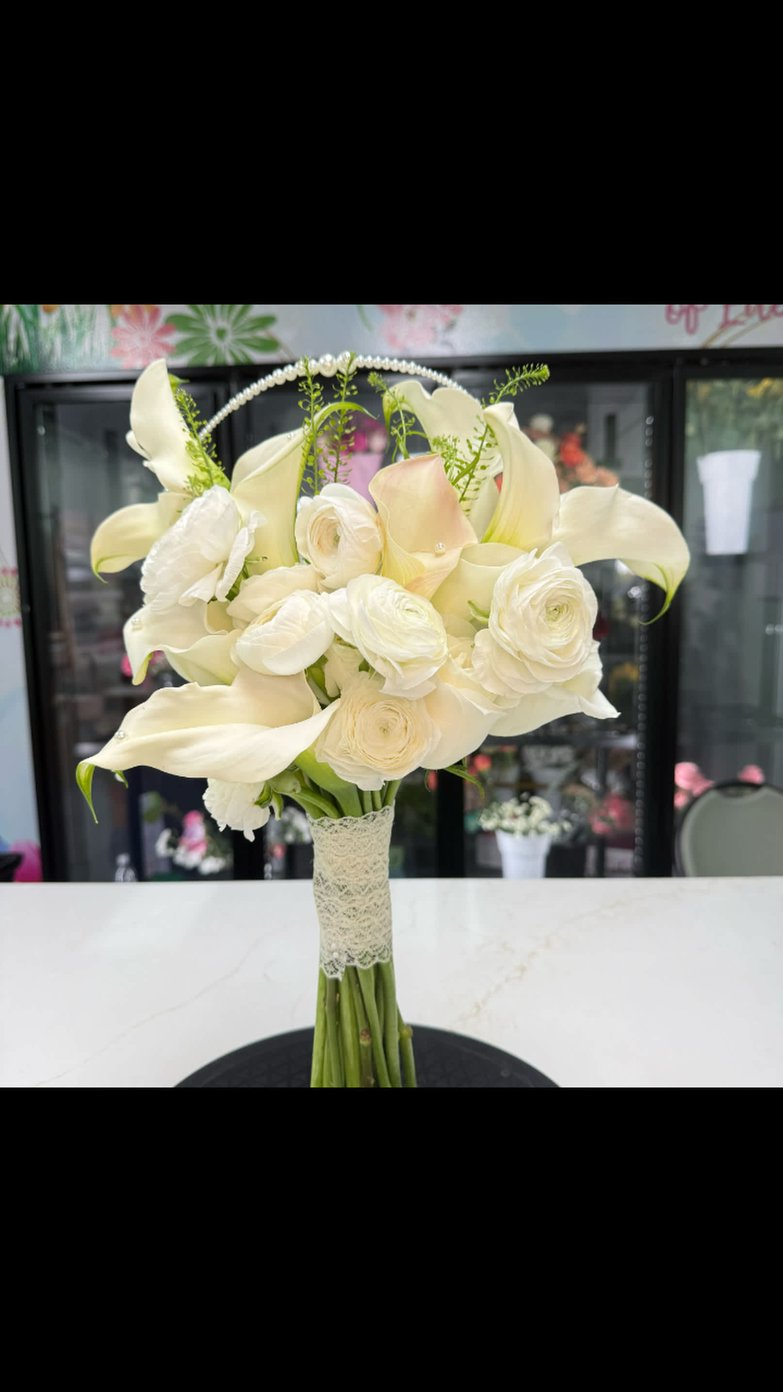 White bridal bouquet with calla lilies, ranunculus, and roses