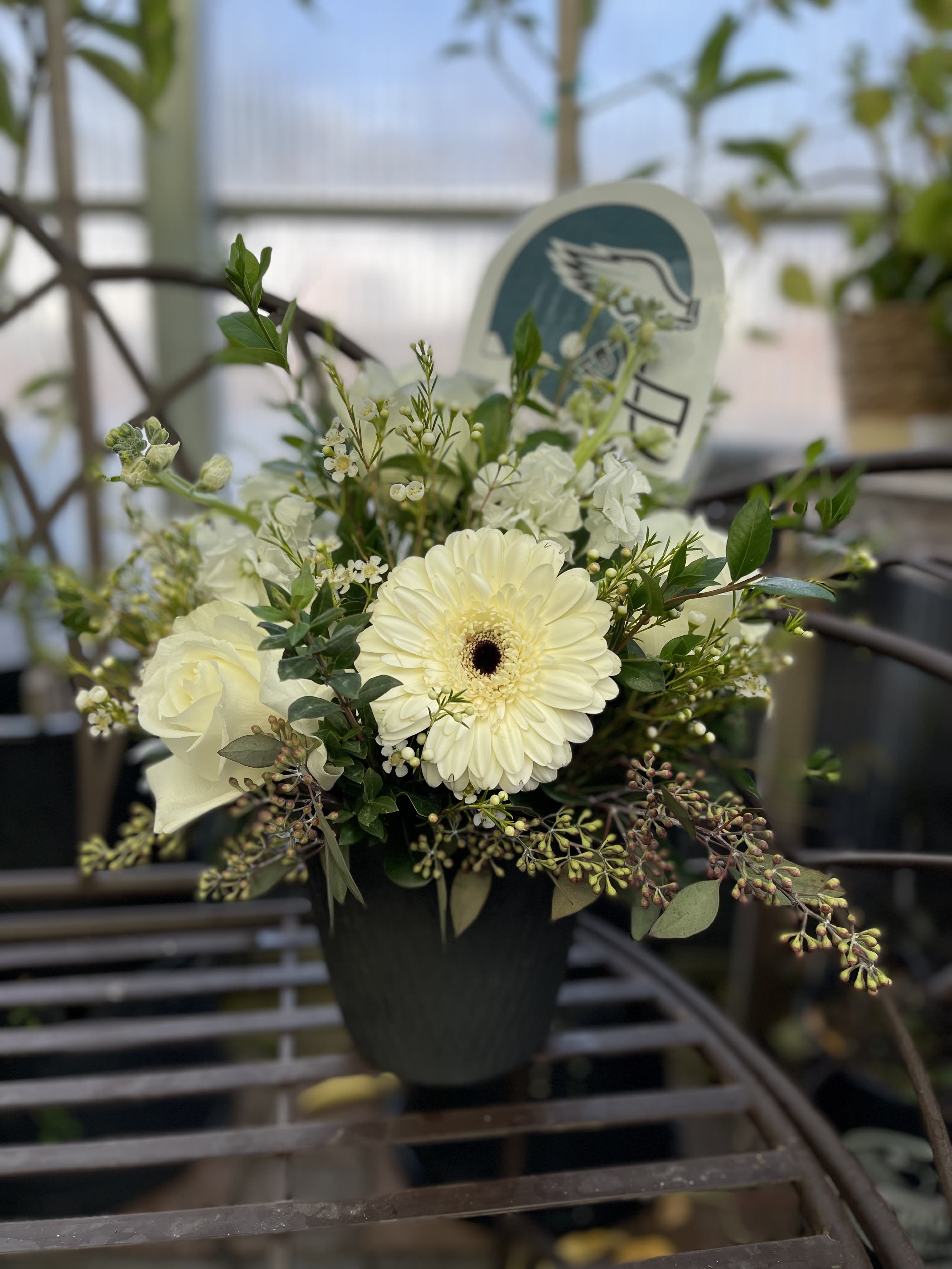 White flowers arranged in a black pot with greenery
