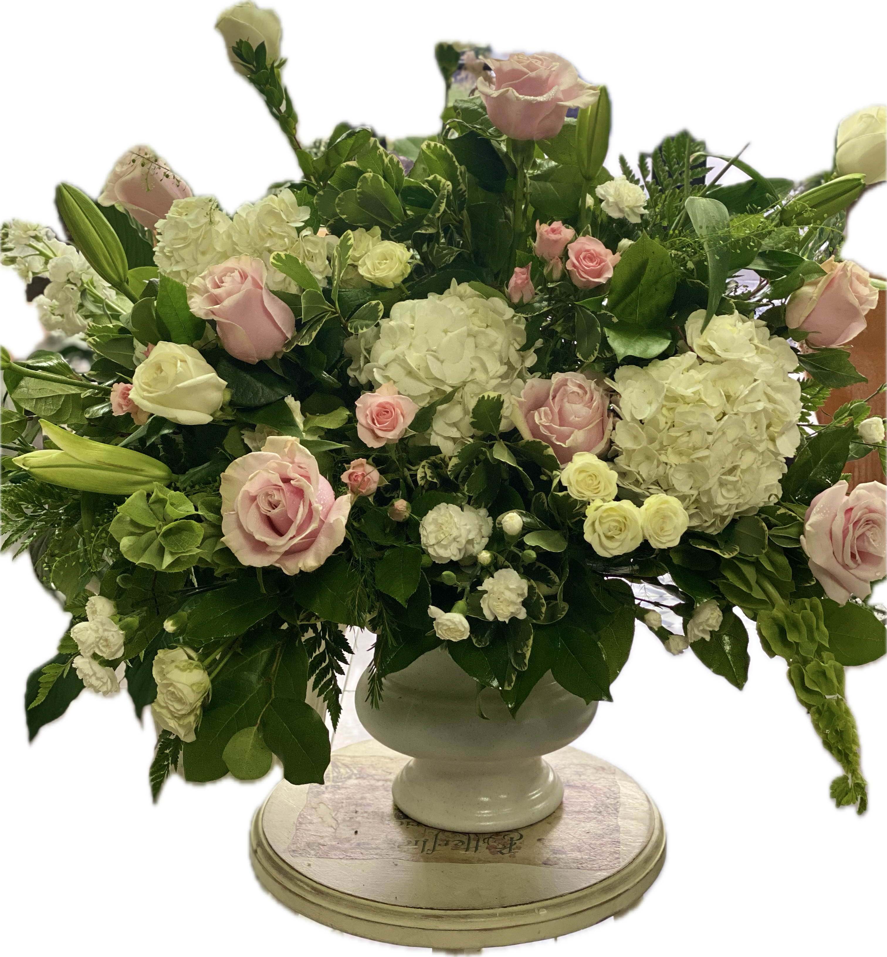 Pink and white roses with hydrangeas in a white urn vase