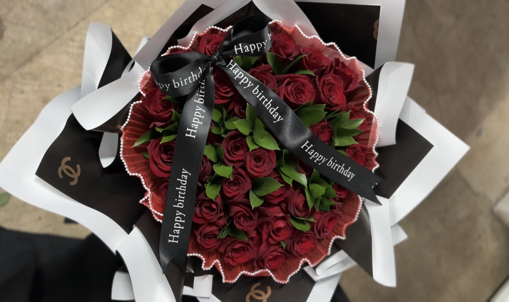 Bouquet of red roses wrapped with black and white paper and birthday ribbons