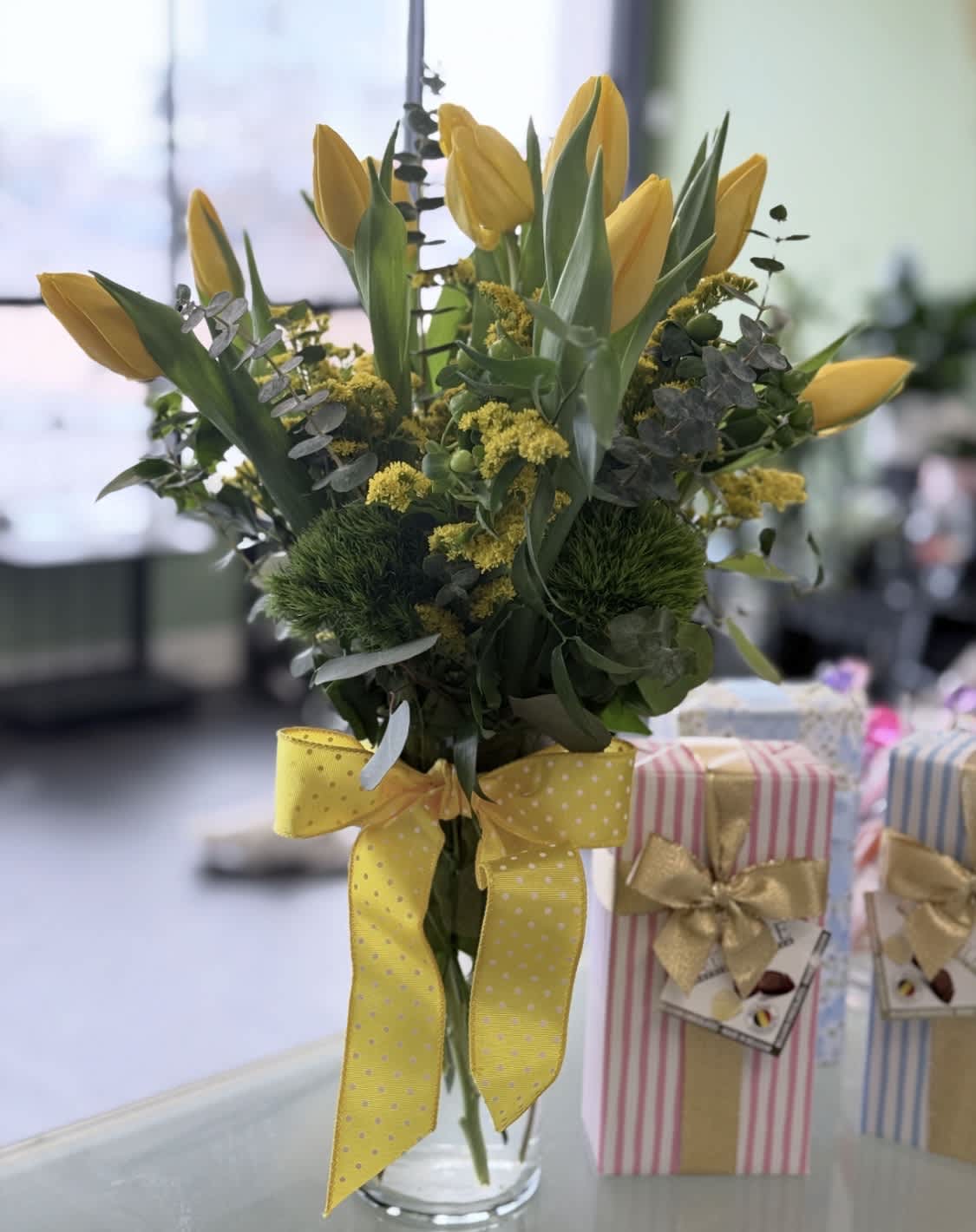Yellow tulips in a clear glass vase with a yellow ribbon