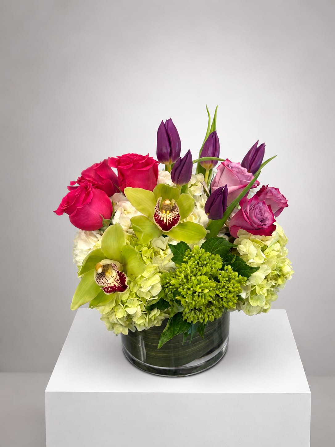 Pink roses and green orchids arranged in a glass vase