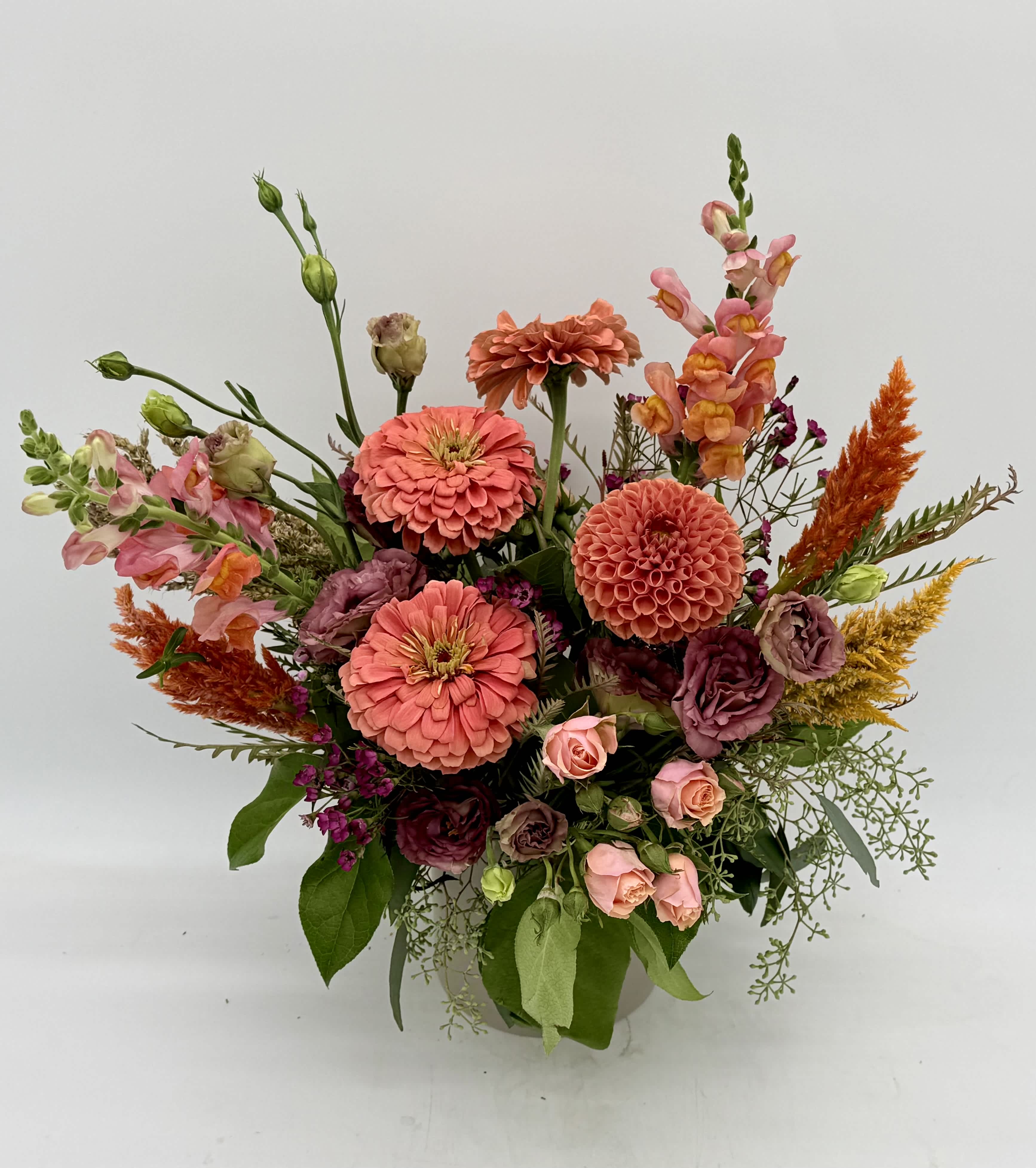 Mixed bouquet of coral, pink, and orange flowers in a vase