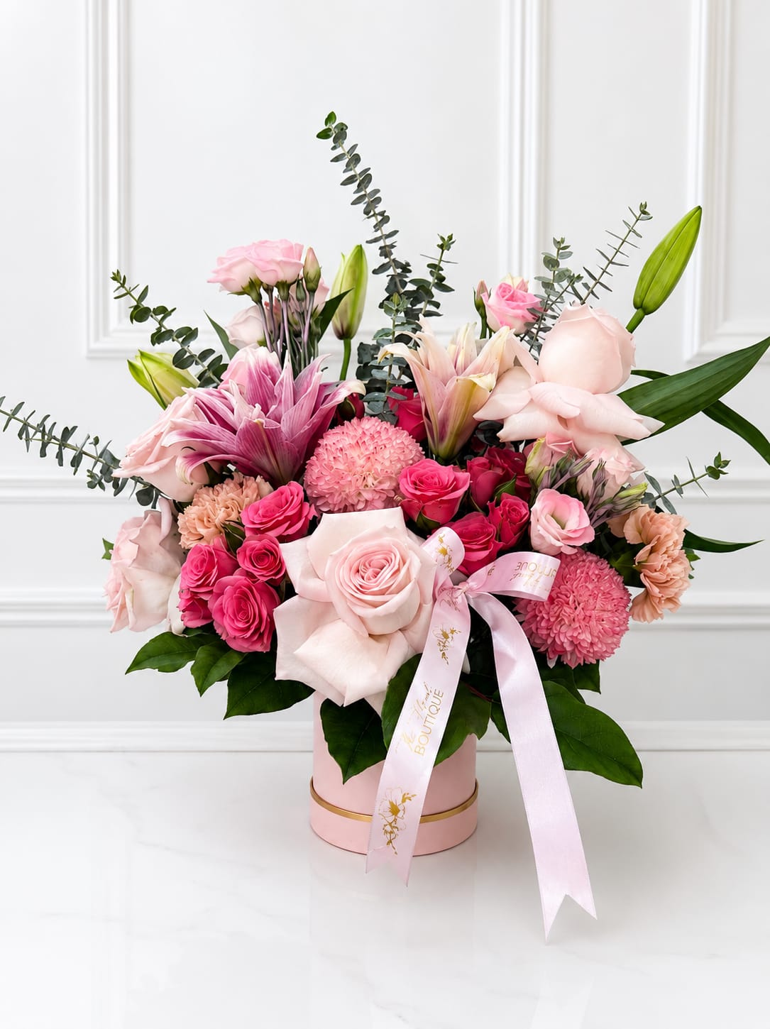 Pink and white mixed flower arrangement in a round box with a ribbon