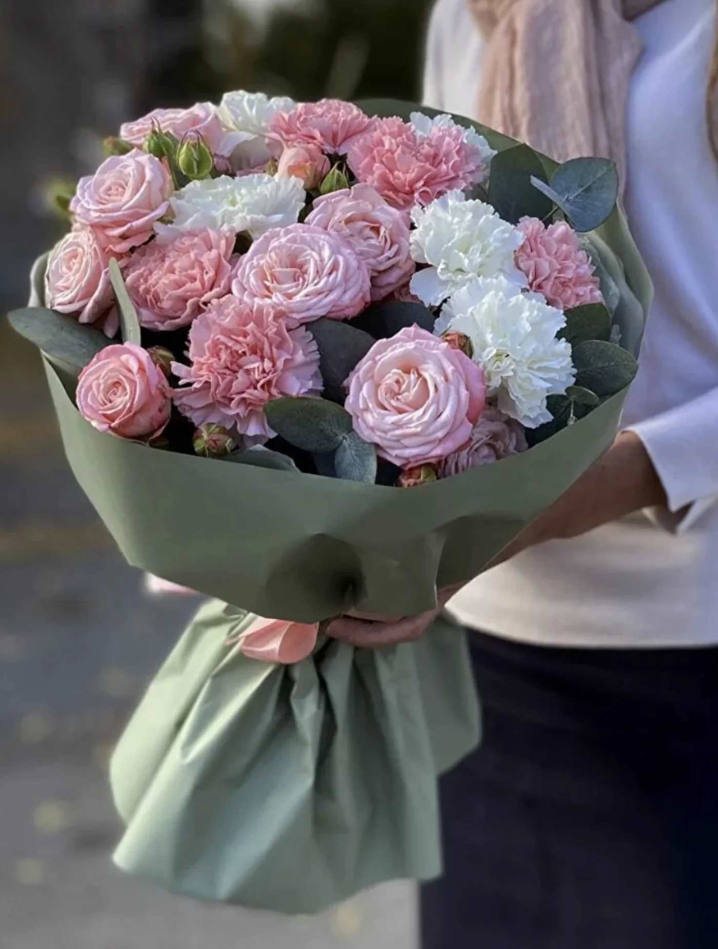 Bouquet of pink roses and white carnations wrapped in green paper