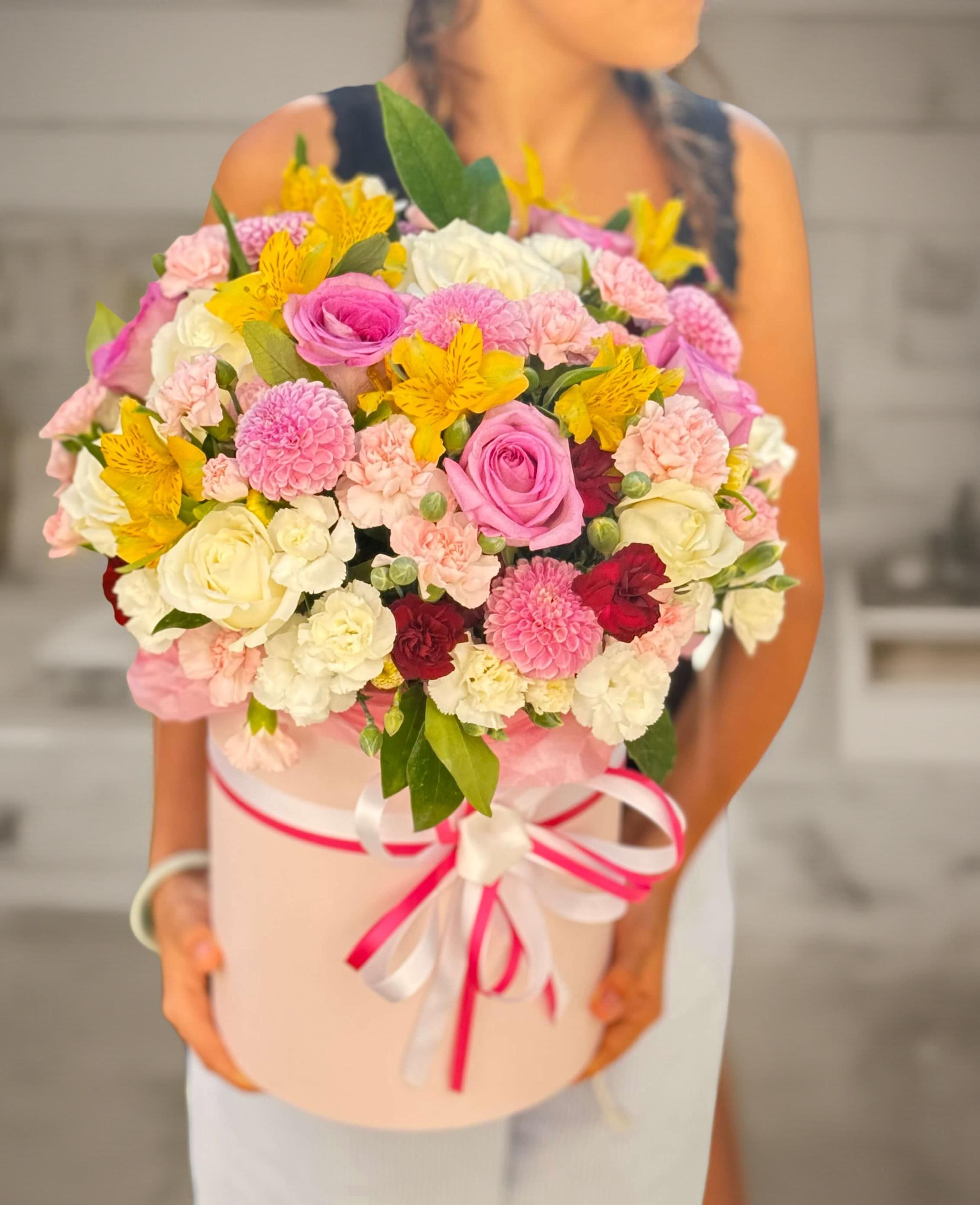 Large bouquet of pink, white, yellow, and red flowers in a pink hat box