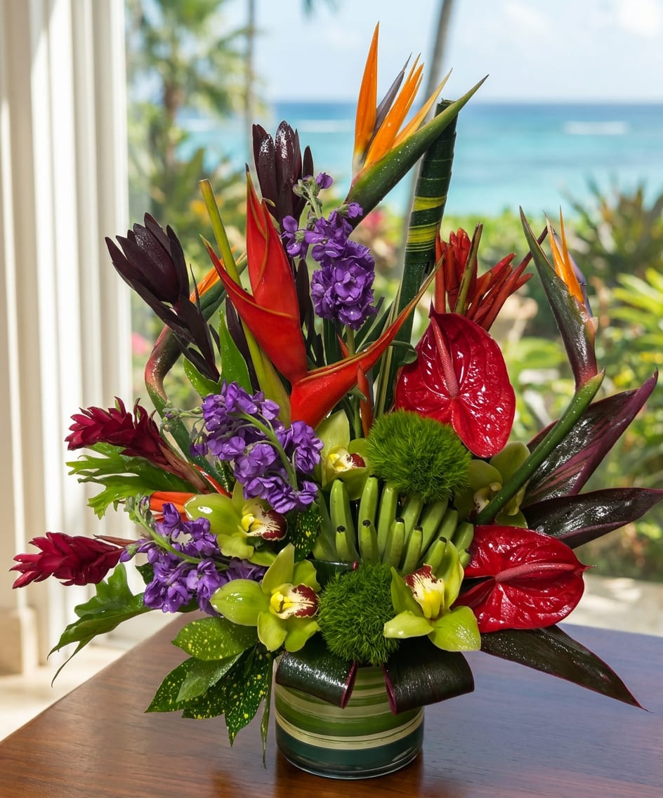 Tropical arrangement with red anthuriums, purple flowers, and bird of paradise in a striped vase.