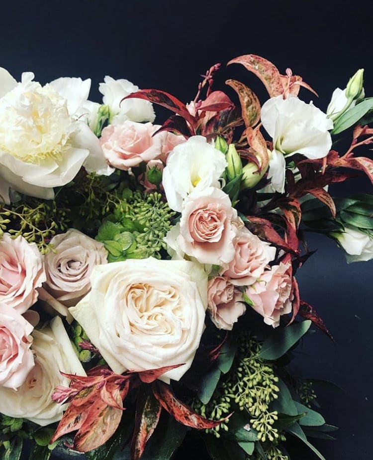 Bouquet of pale pink and white roses with white blooms and dark foliage