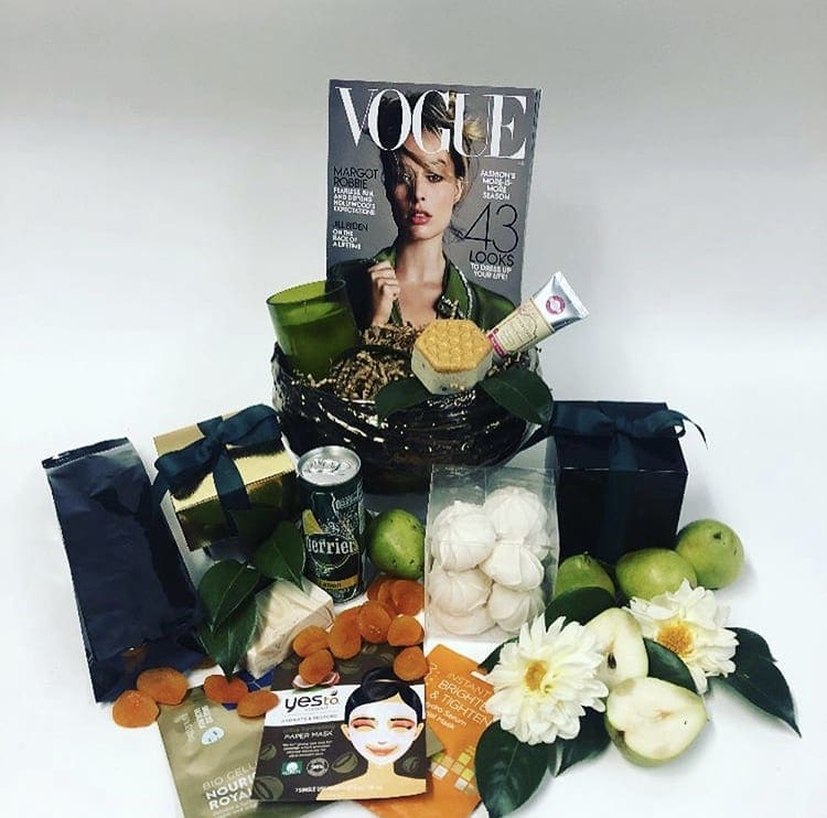 Gift basket with magazines, snacks, cosmetics, and white flowers