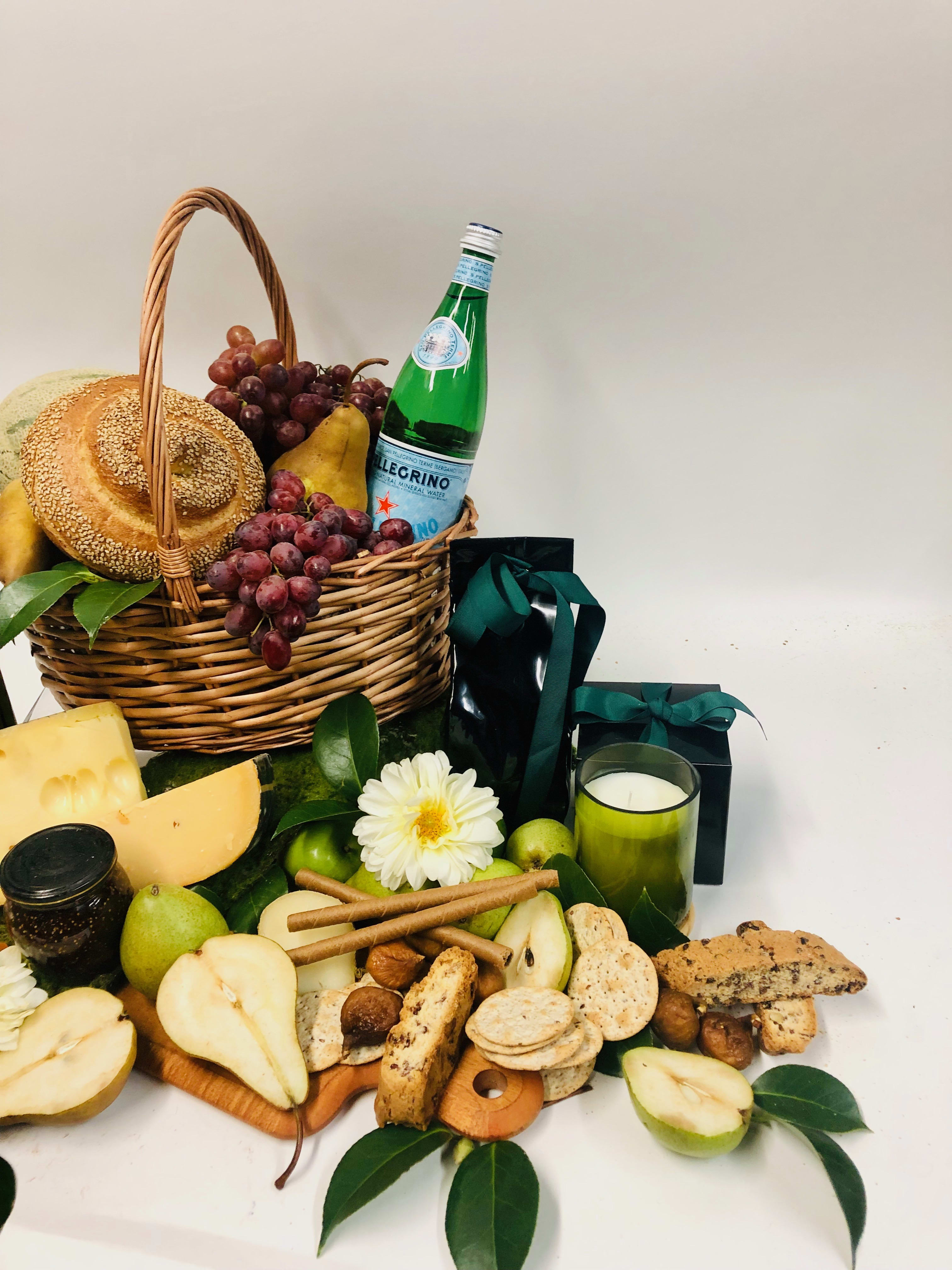 Gift basket with fruit, bread, cheese, crackers, and a candle