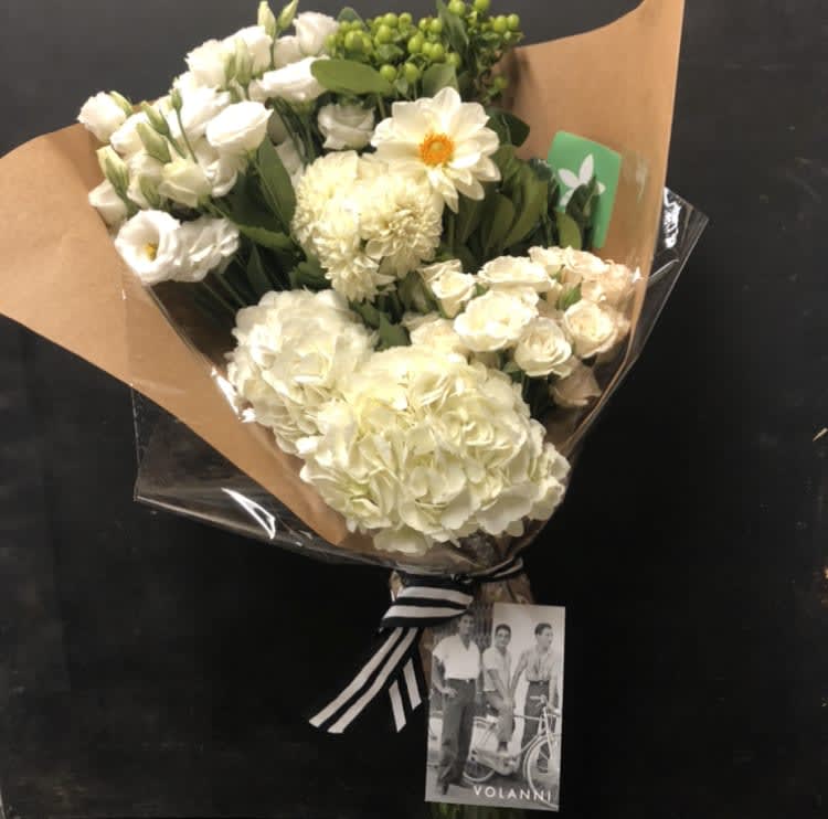 Bouquet of white flowers wrapped in brown paper with a striped ribbon