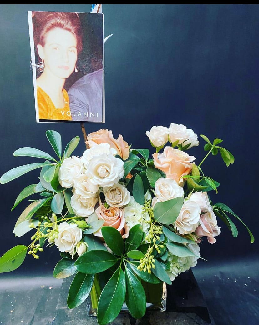 Floral arrangement of cream and peach roses with a photo card