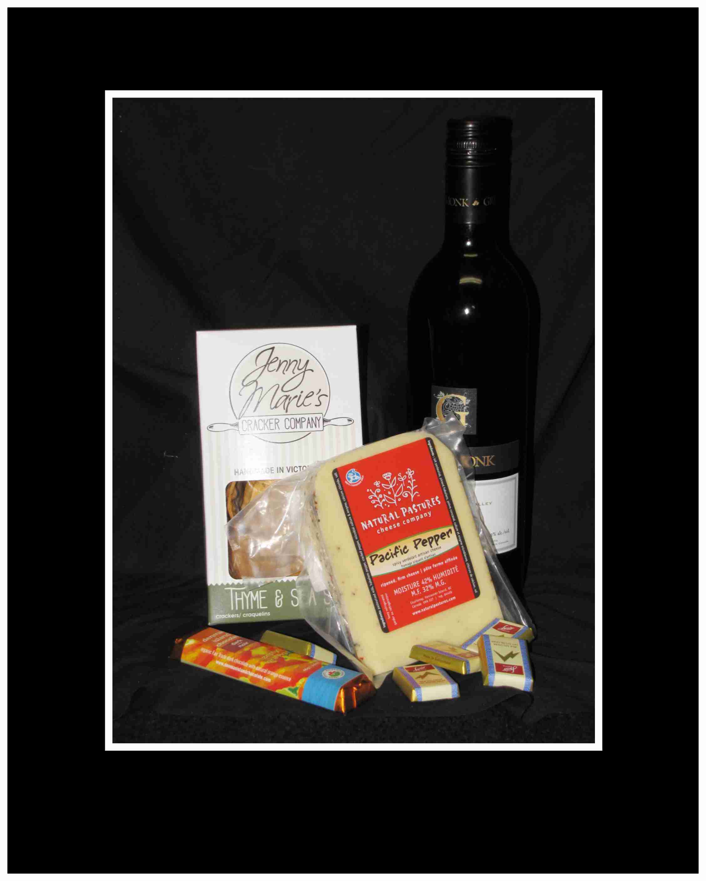 Wine bottle with crackers, cheese, and chocolates on a black background