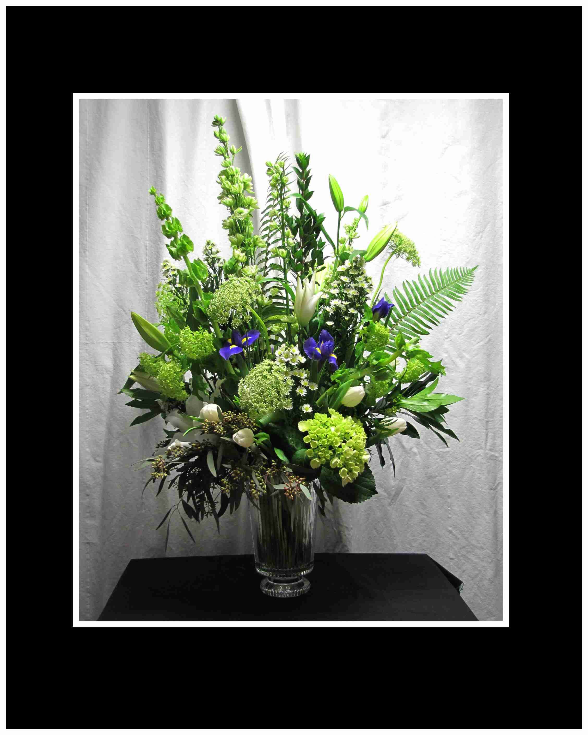 Tall green and white floral arrangement in a clear glass vase