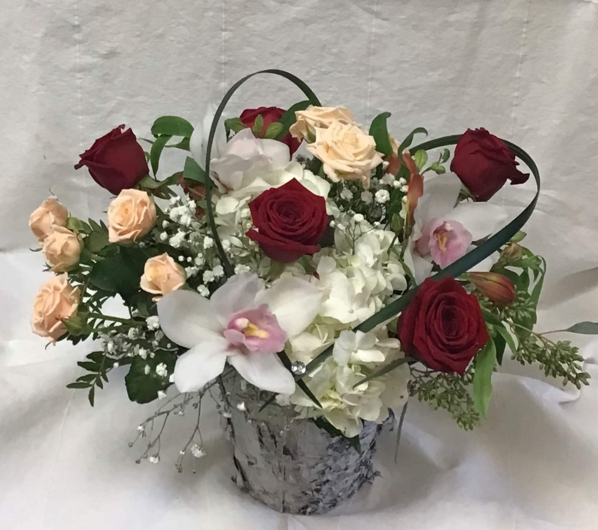 Mixed roses and orchids in a silver container