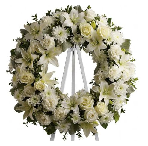 White floral wreath with lilies, roses, and daisies on a ribbon stand