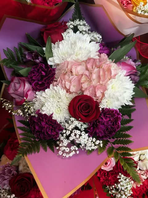 Bouquet of pink, white, and red flowers wrapped in pink paper