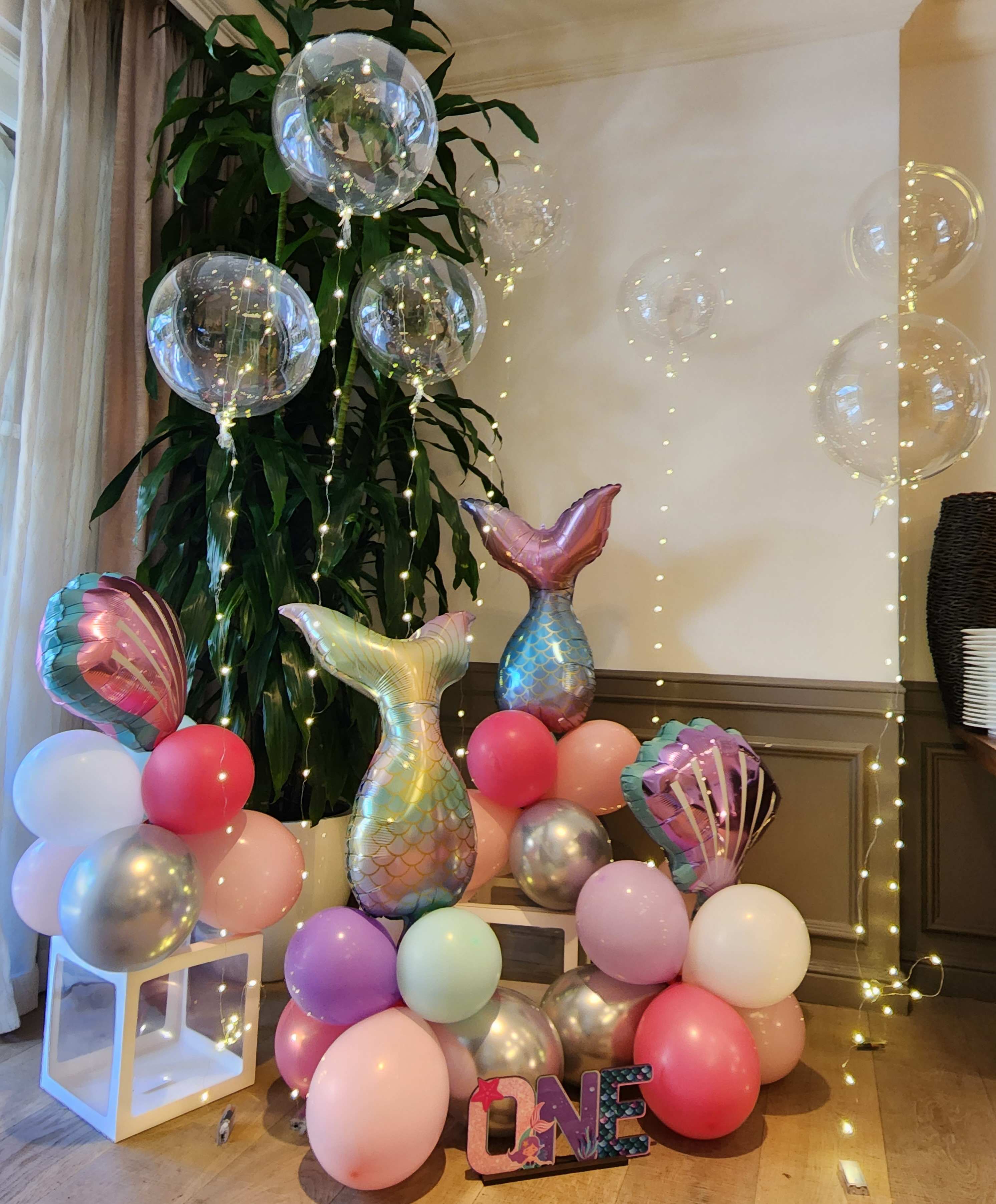 Mermaid-themed balloon display with pastel balloons and clear balloons with lights